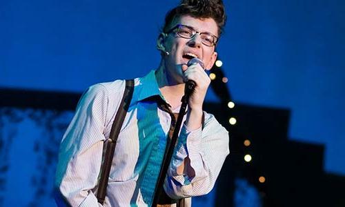 male student singing at a microphone